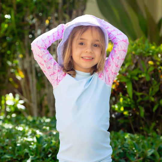 Child wearing blue and pink rashguard with seashells